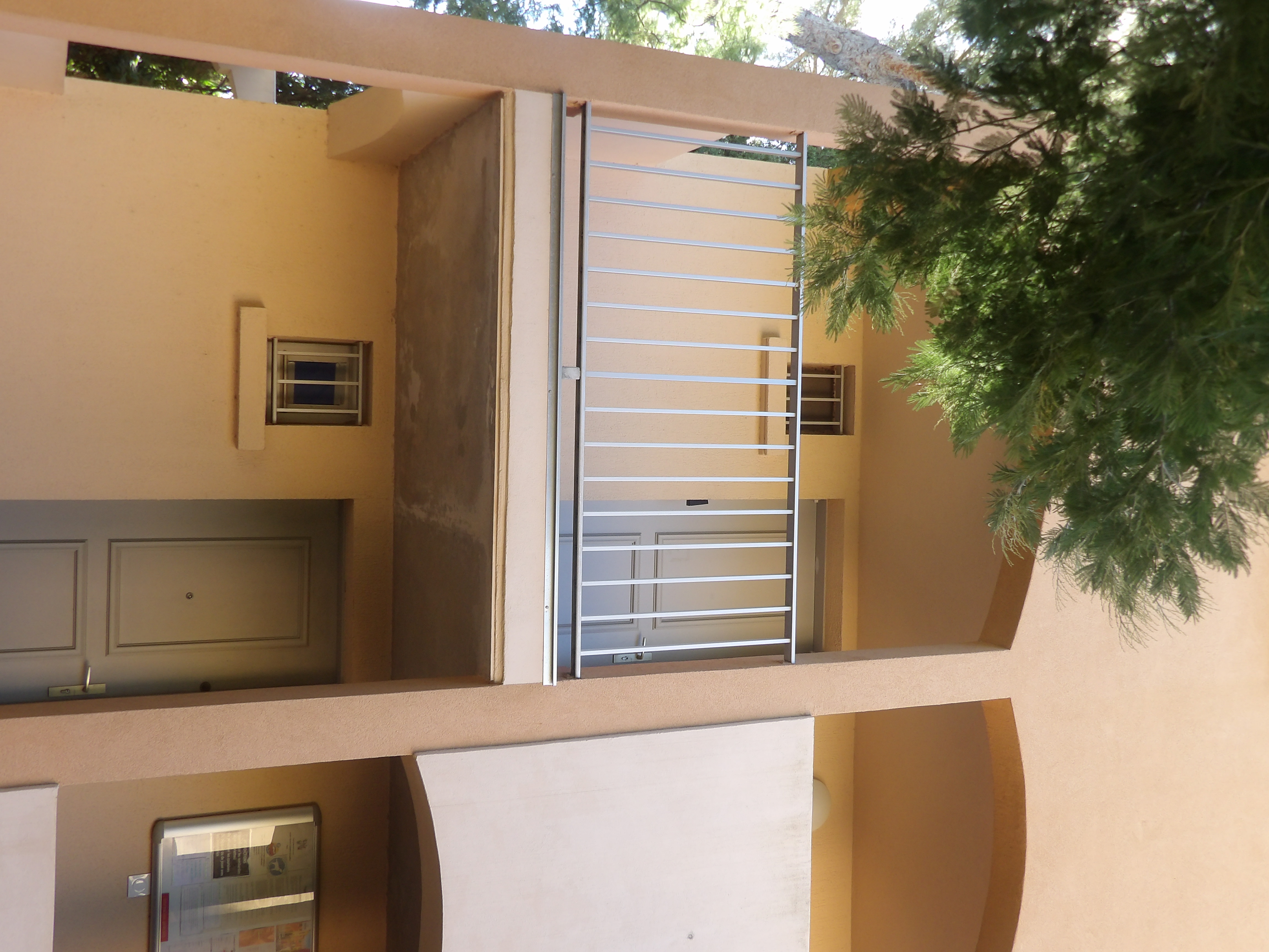 Vue rapprochée des portes d'entrée et balcons de la résidence sous les pins