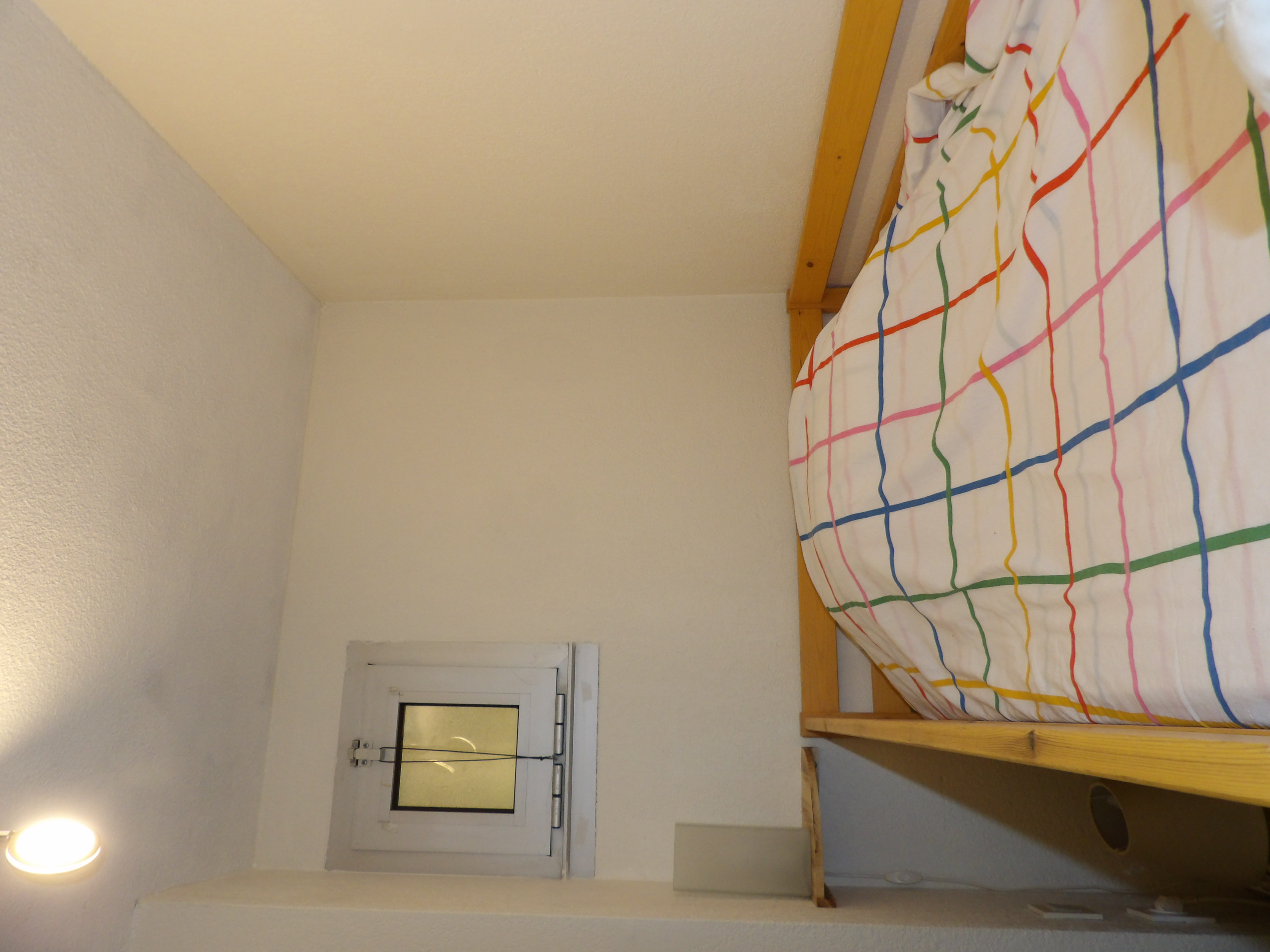 Lit en bois avec couvre-lit rayé multicolore dans la chambre lit superposé du logement