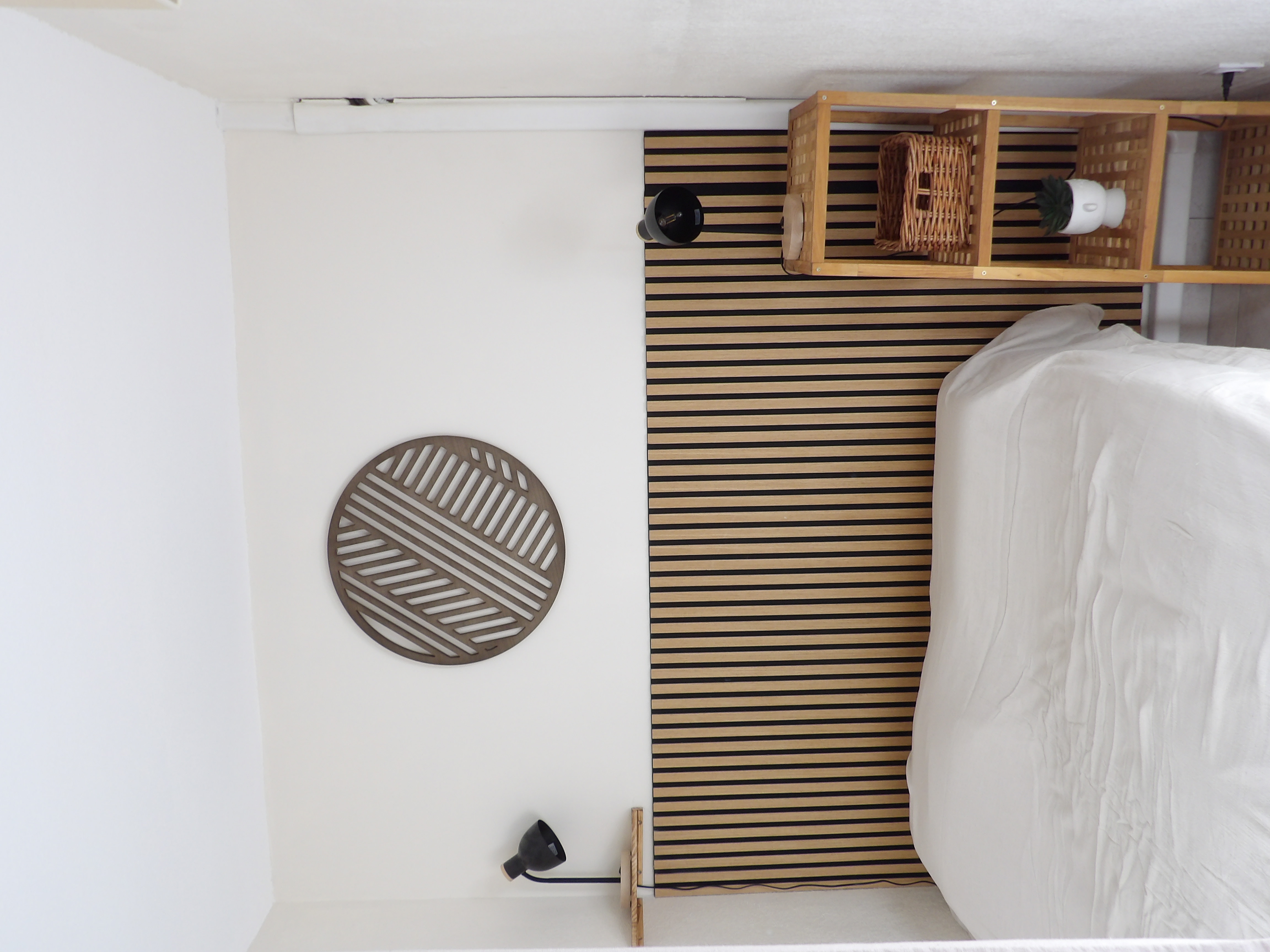 Chambre avec tête de lit en claire-voie bois et noir, décoration murale circulaire et étagère en bois