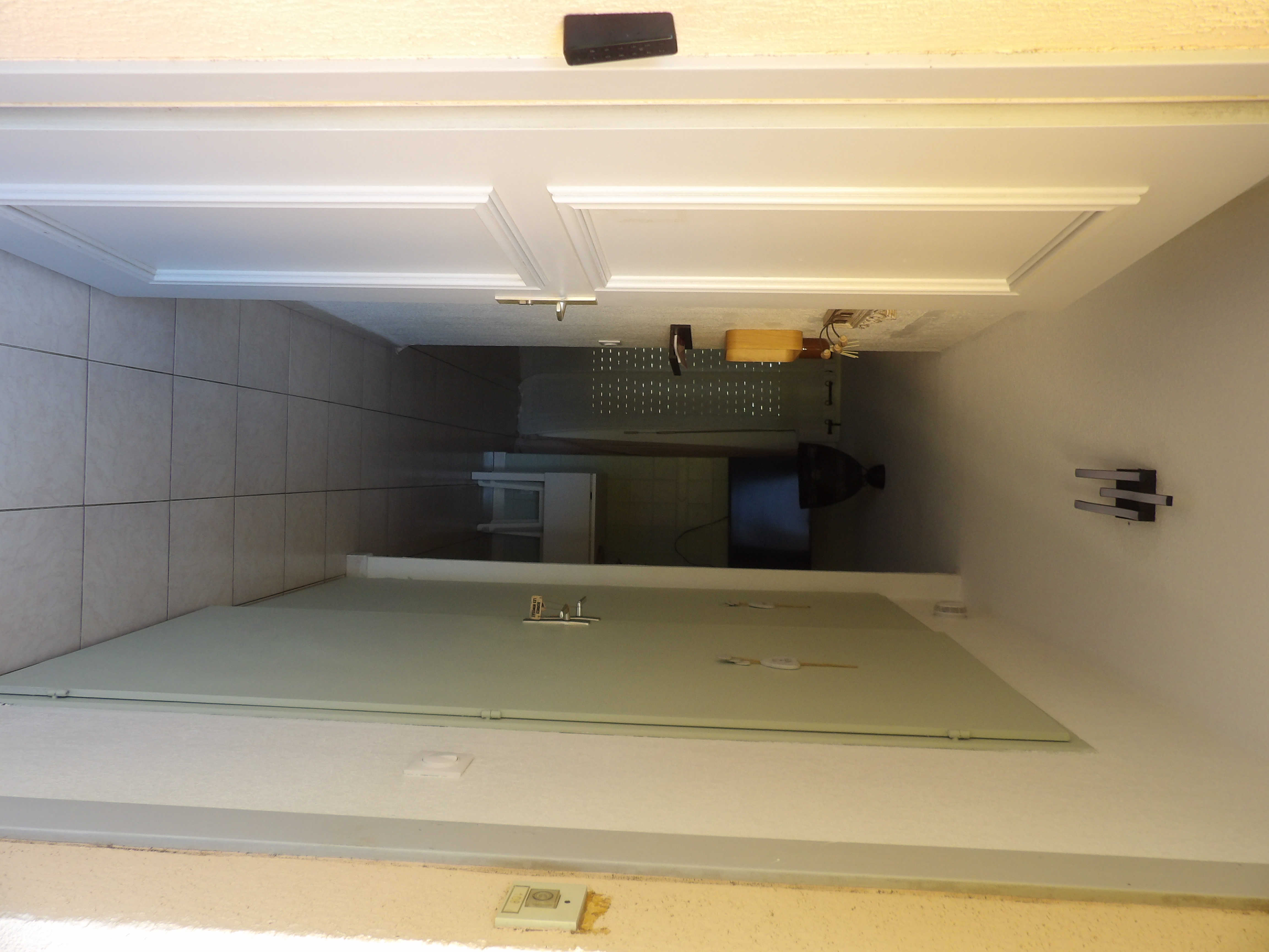 Vue du couloir d'entrée du logement, sol carrelé et portes donnant sur les pièces